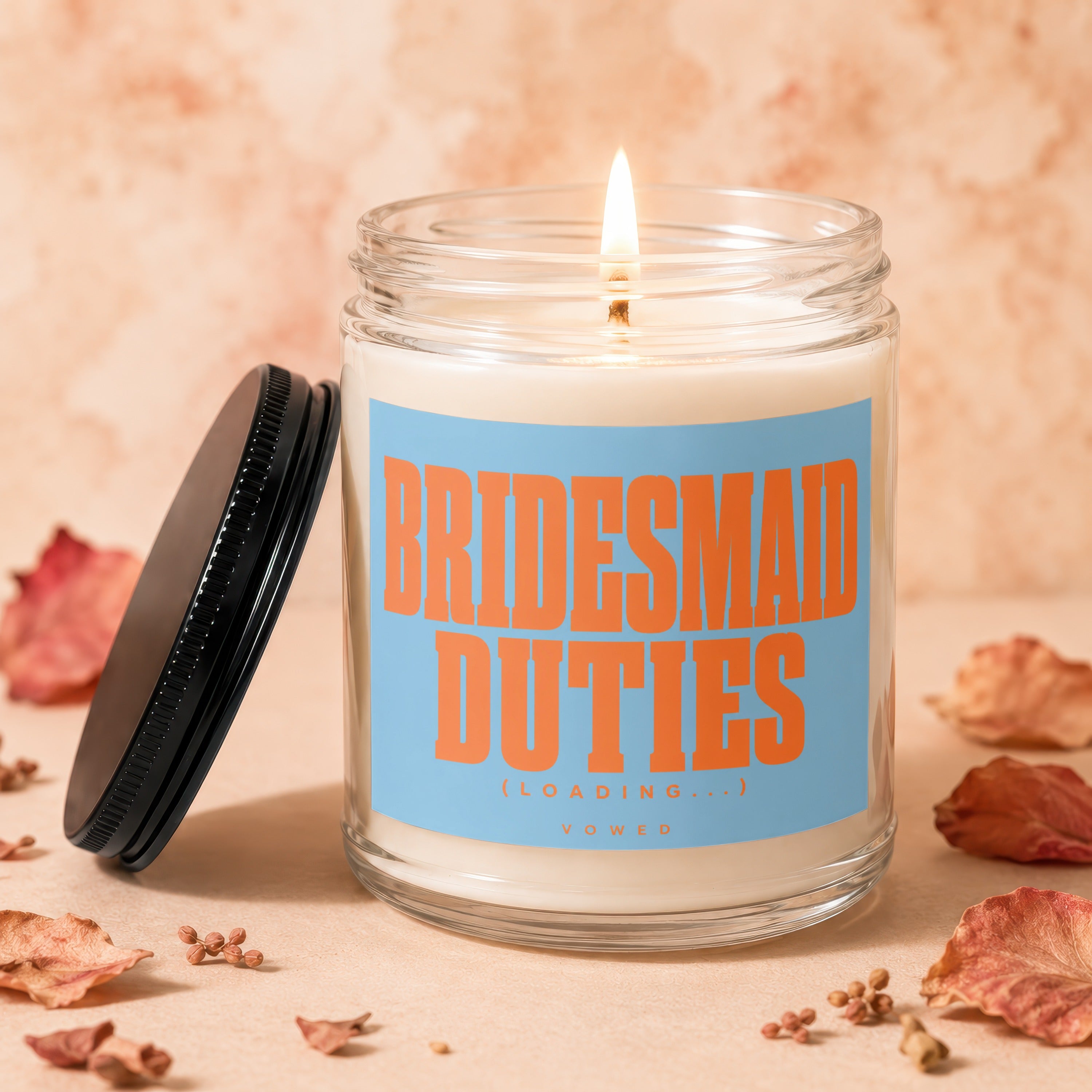 Lit candle in glass jar with orange text "BRIDESMAID DUTIES (LOADING...) VOWED".