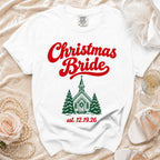 White t-shirt featuring red Christmas Bride text and a green church graphic with pine trees.