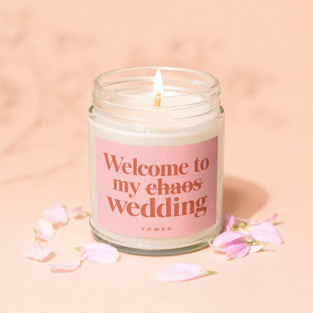 Candle with pink label reading "Welcome to my chaos wedding VOWED".
