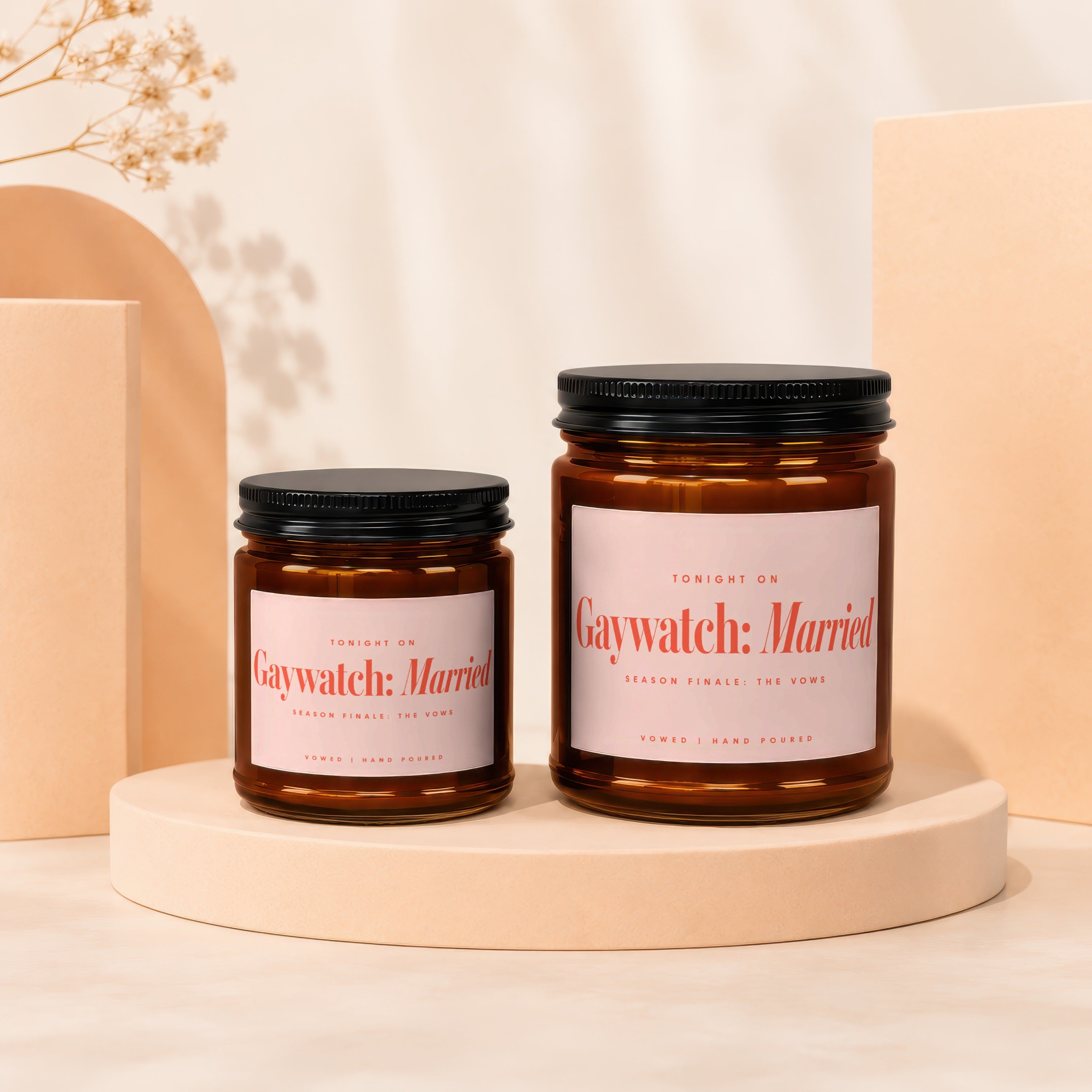 Two amber glass candles with pink labels reading "Gaywatch: Married" sit on pedestals.