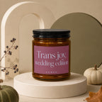 Amber candle in glass jar with pink label reading "Trans joy, wedding edition Vowed".