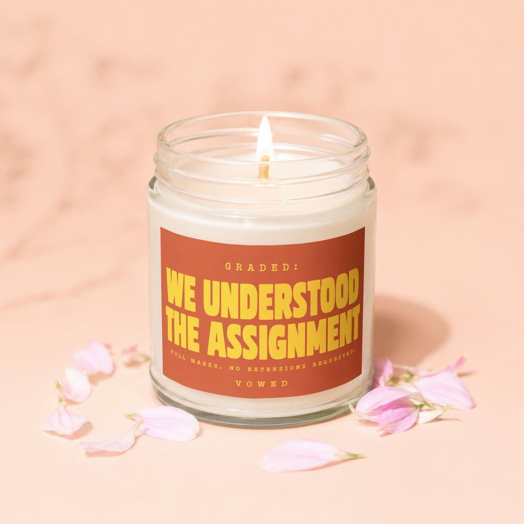 Candle with text "Graded: We Understood the Assignment. Full Marks. No Extensions Requested. Vowed."