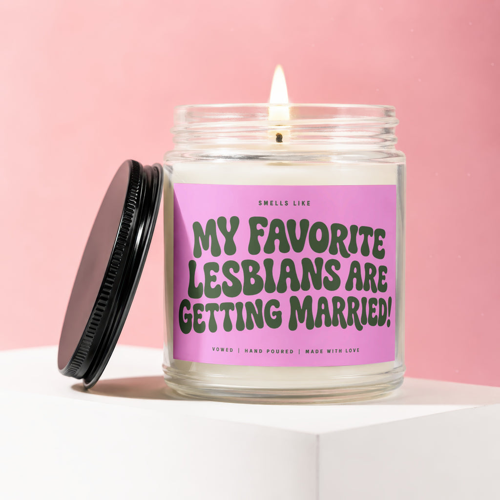 Glass jar candle with pink label reading "My Favorite Lesbians Are Getting Married!"