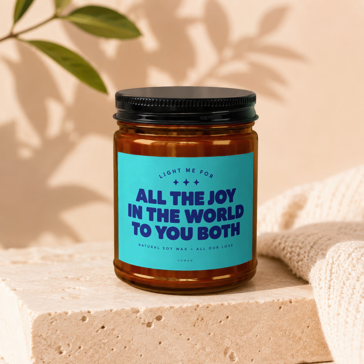 Amber jar candle with blue label reading "All The Joy In The World To You Both."