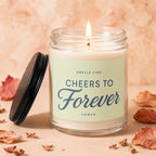 A lit "Cheers To Forever Vowed" candle in a glass jar with a black lid nearby.