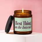 Amber candle with lit flame, "Best Thing on the Internet" text, and black lid.