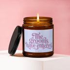 Amber candle with lit flame, white label reads "The grooms have entered VOWED".