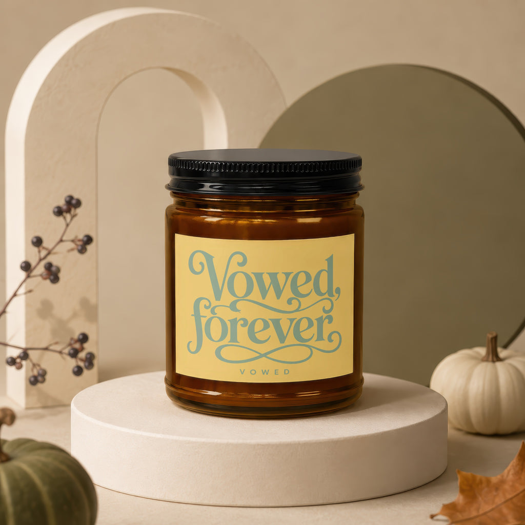 Amber candle with yellow label reading "Vowed, forever" on a display stand.