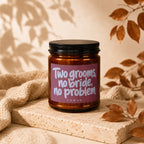 Amber jar candle with pink label reads "Two grooms, no bride, no problem" and "VOWED".