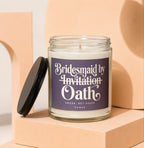 Glass jar candle with purple label reading "Bridesmaid by Invitation Oath".