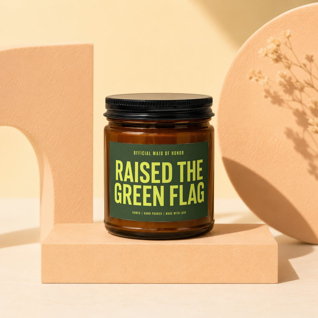 Candle with black lid, label reads "Raised the Green Flag".