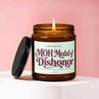 Brown glass candle with lit flame, black lid, and label reading "MOH Medal of Dishonor."
