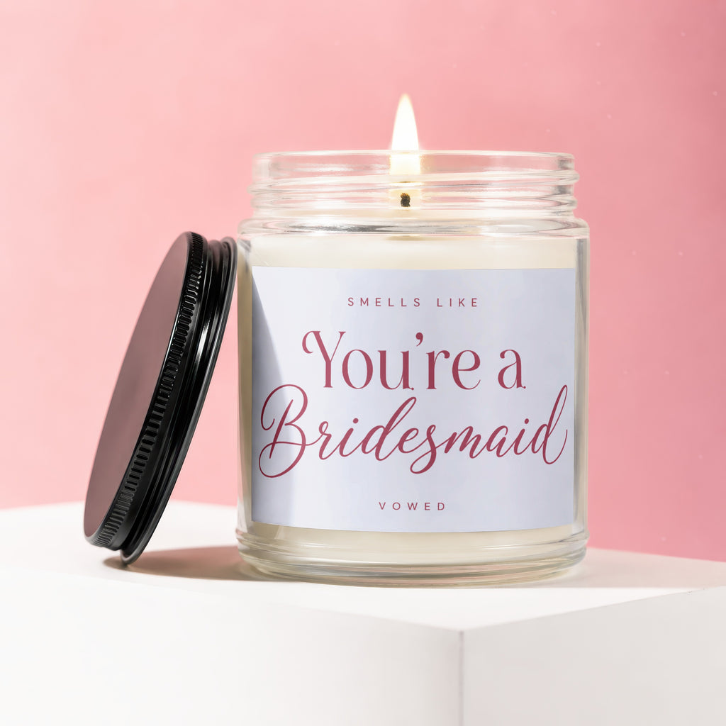 Jar candle with a lit flame and a label that reads "Smells Like You're a Bridesmaid."