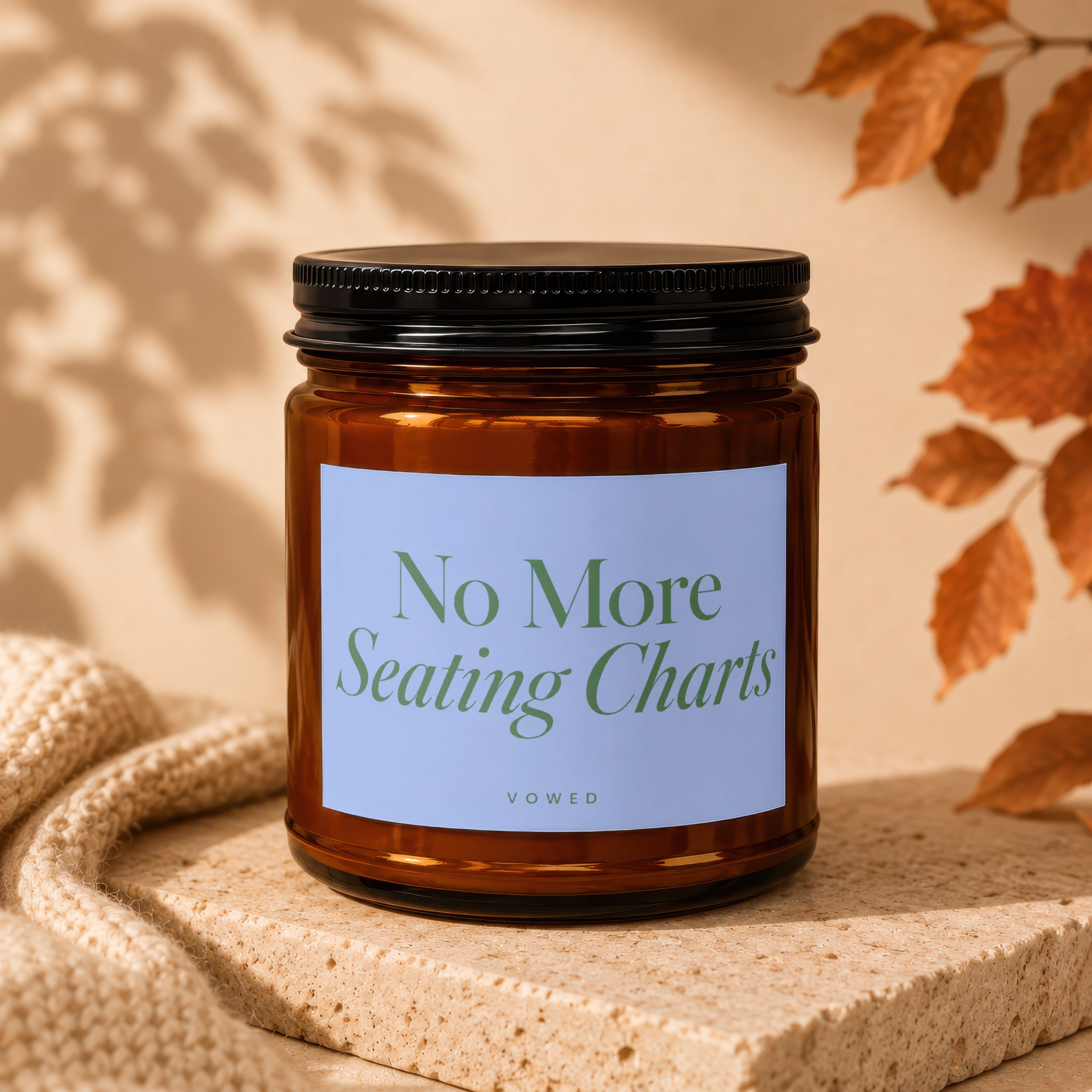 Amber glass candle with "No More Seating Charts" text on blue label.