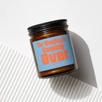 Amber jar candle with black lid, light blue label reads "The Wedding Is Coming Over Finally Vowed".