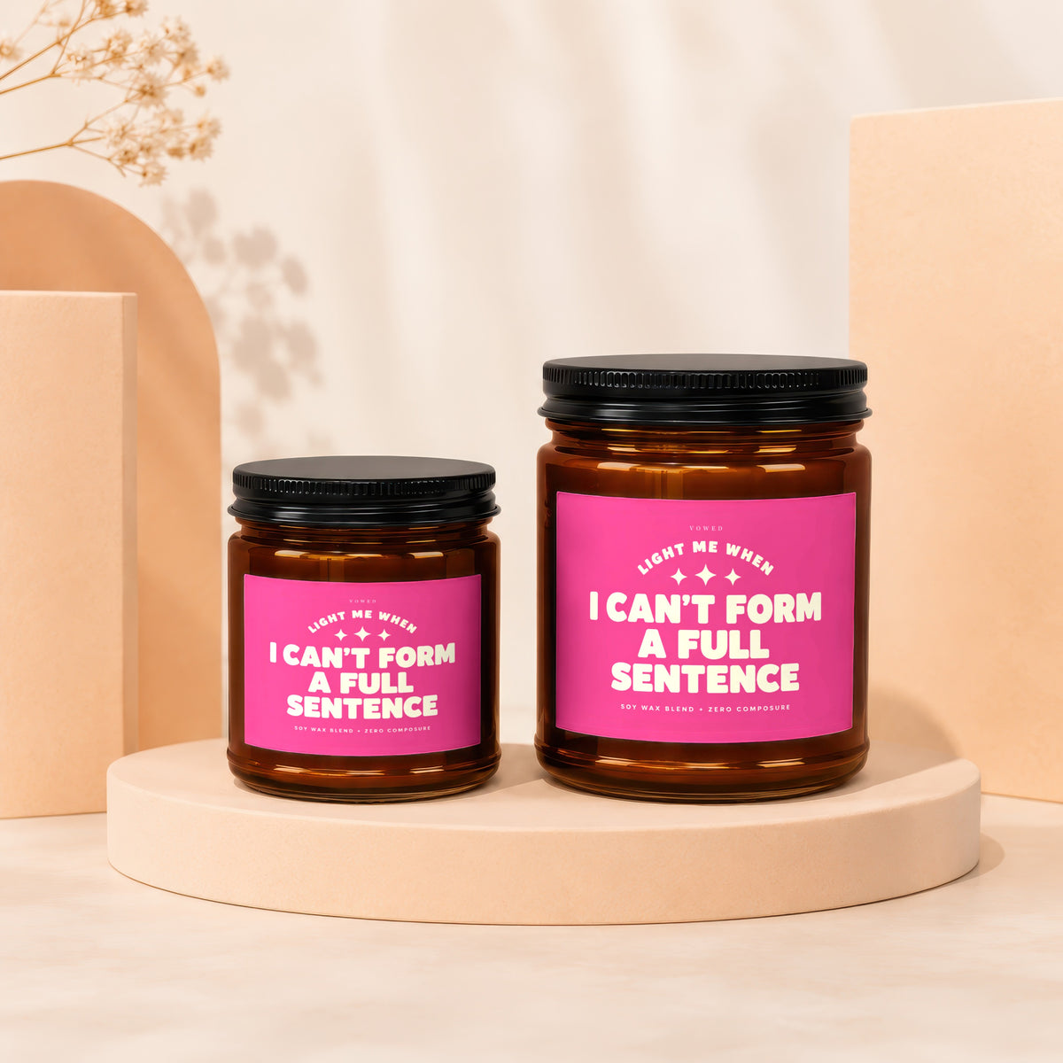 Two amber glass candles with pink labels reading "I CAN'T FORM A FULL SENTENCE."