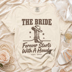 Cream t-shirt featuring brown text reading "The Bride Forever Starts With A Howdy" and a cowboy boot graphic.