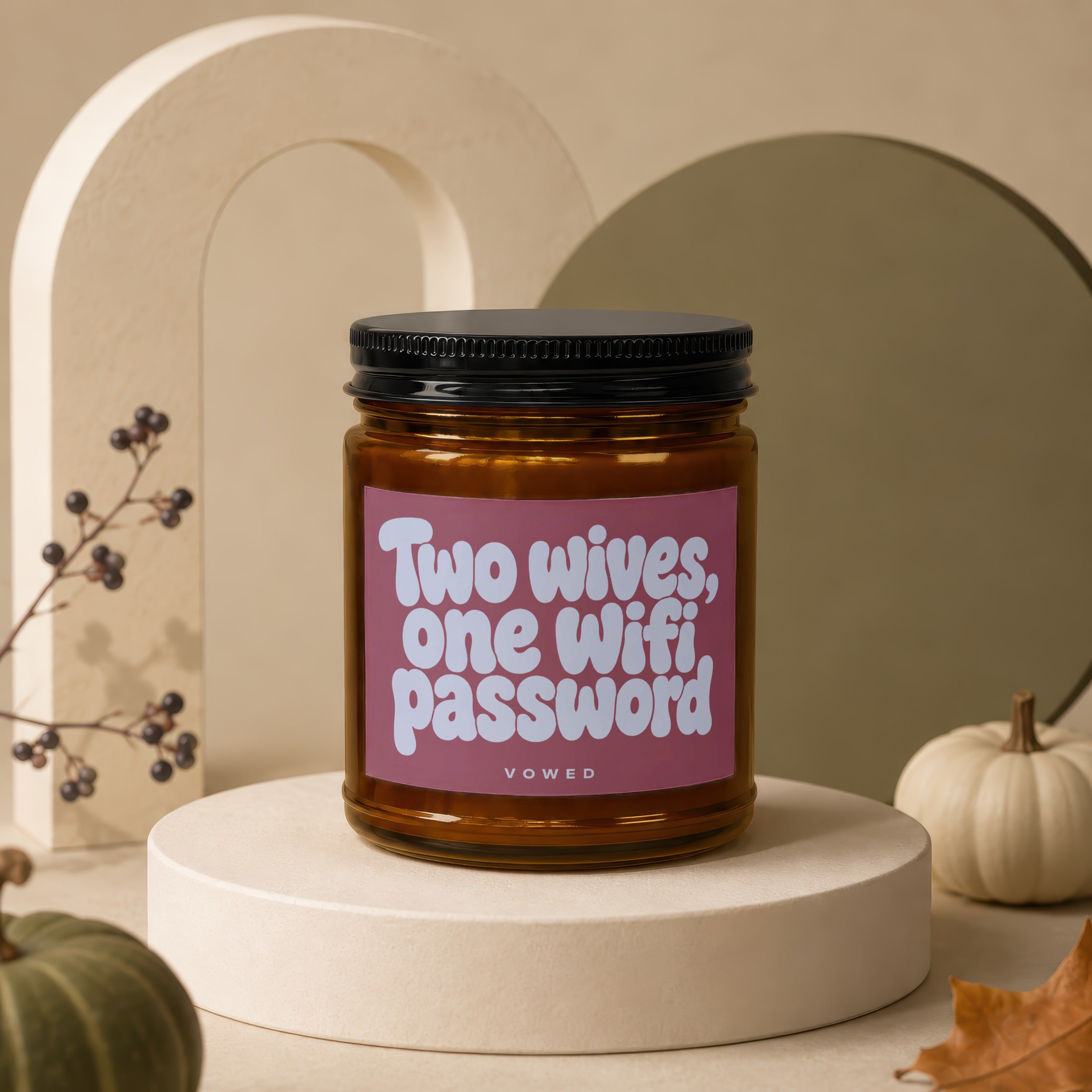 Amber jar candle with a pink label that reads "Two wives, one Wifi password."