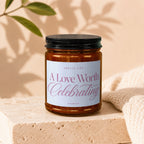 Amber glass candle with a white label reads "Smells Like A Love Worth Celebrating VOWED".