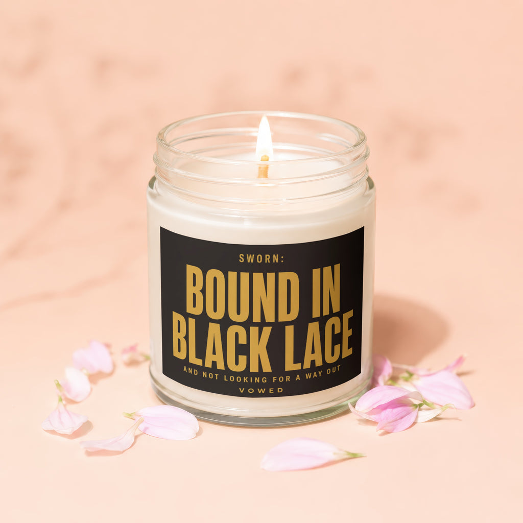 Candle with lit wick and label text "SWORN: BOUND IN BLACK LACE".