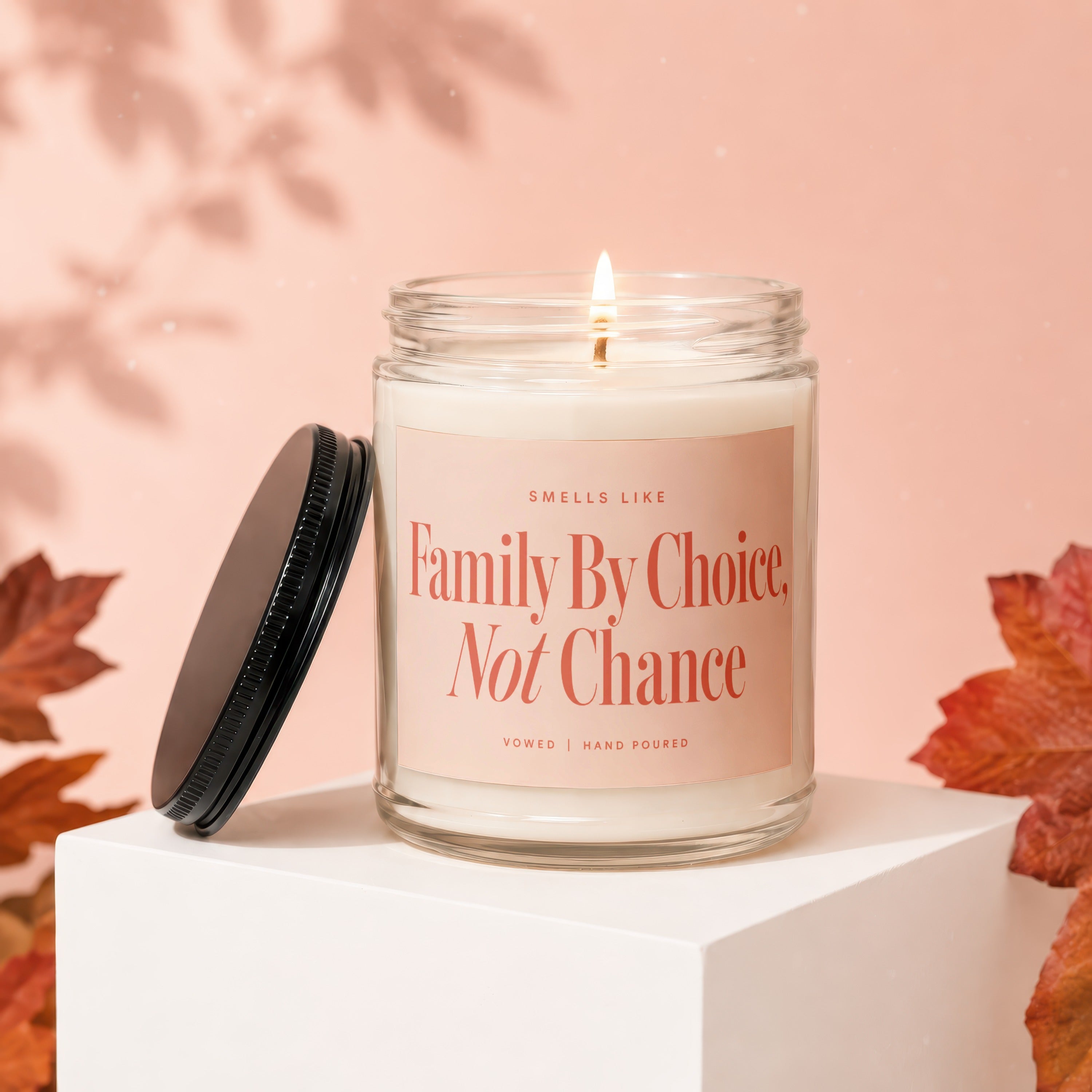 Candle with lit wick and lid off, reads "Family By Choice, Not Chance".