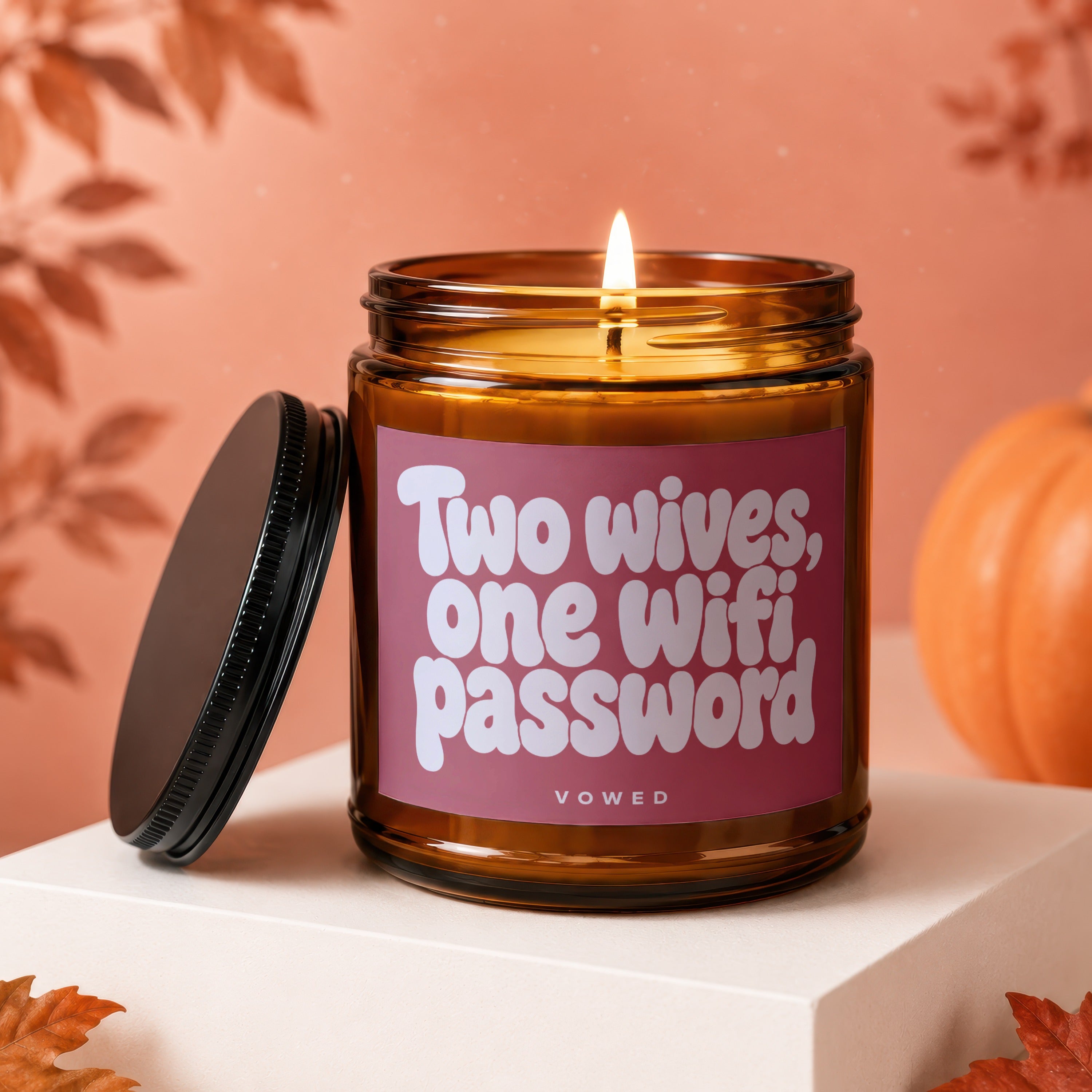 Brown glass candle with lit wick and white text "Two wives, one Wifi password".