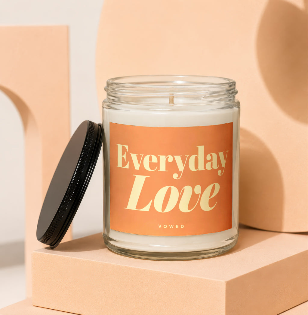 Glass candle with orange label reading "Everyday Love VOWED".
