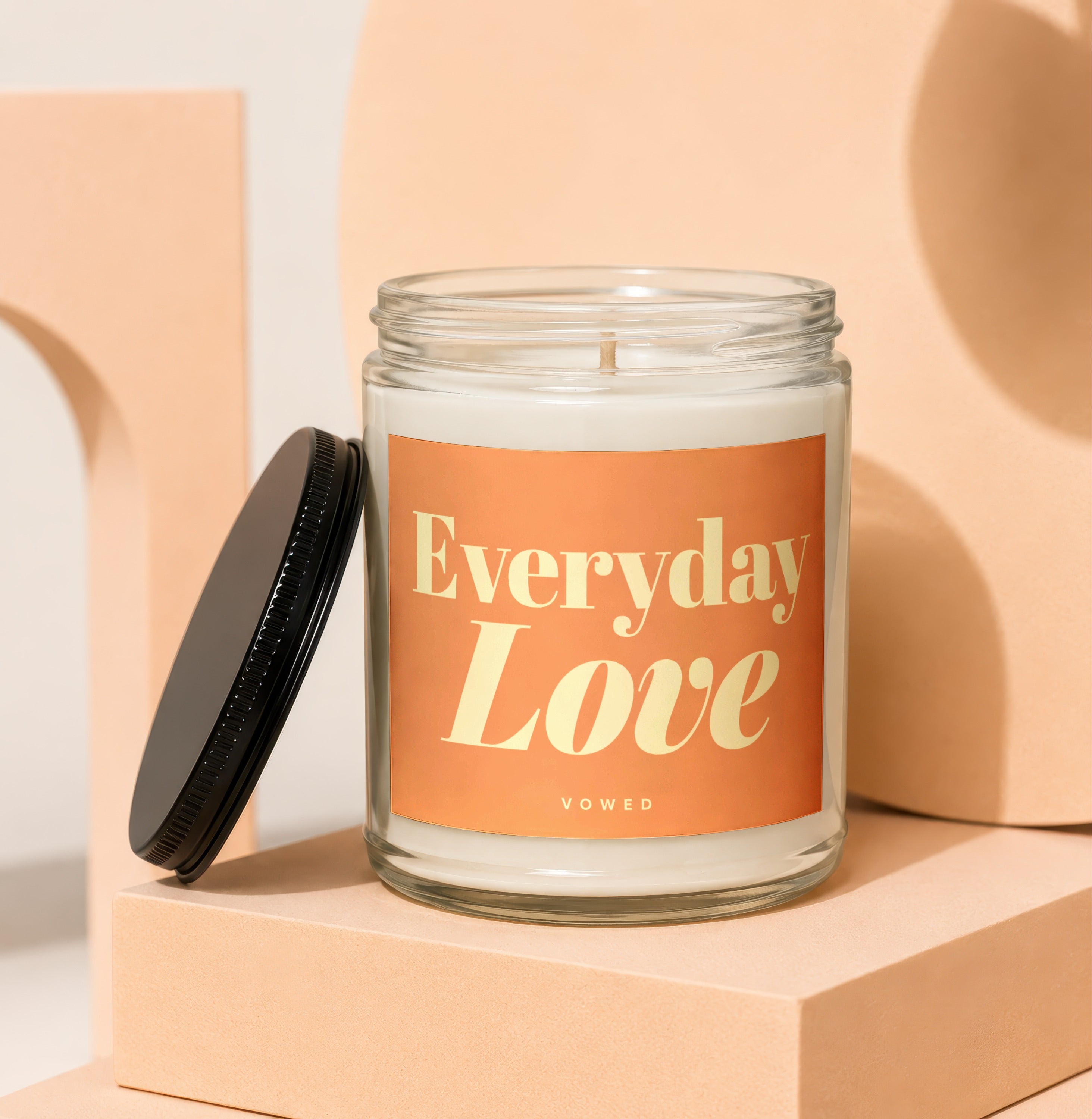 Glass candle with orange label reading "Everyday Love VOWED".