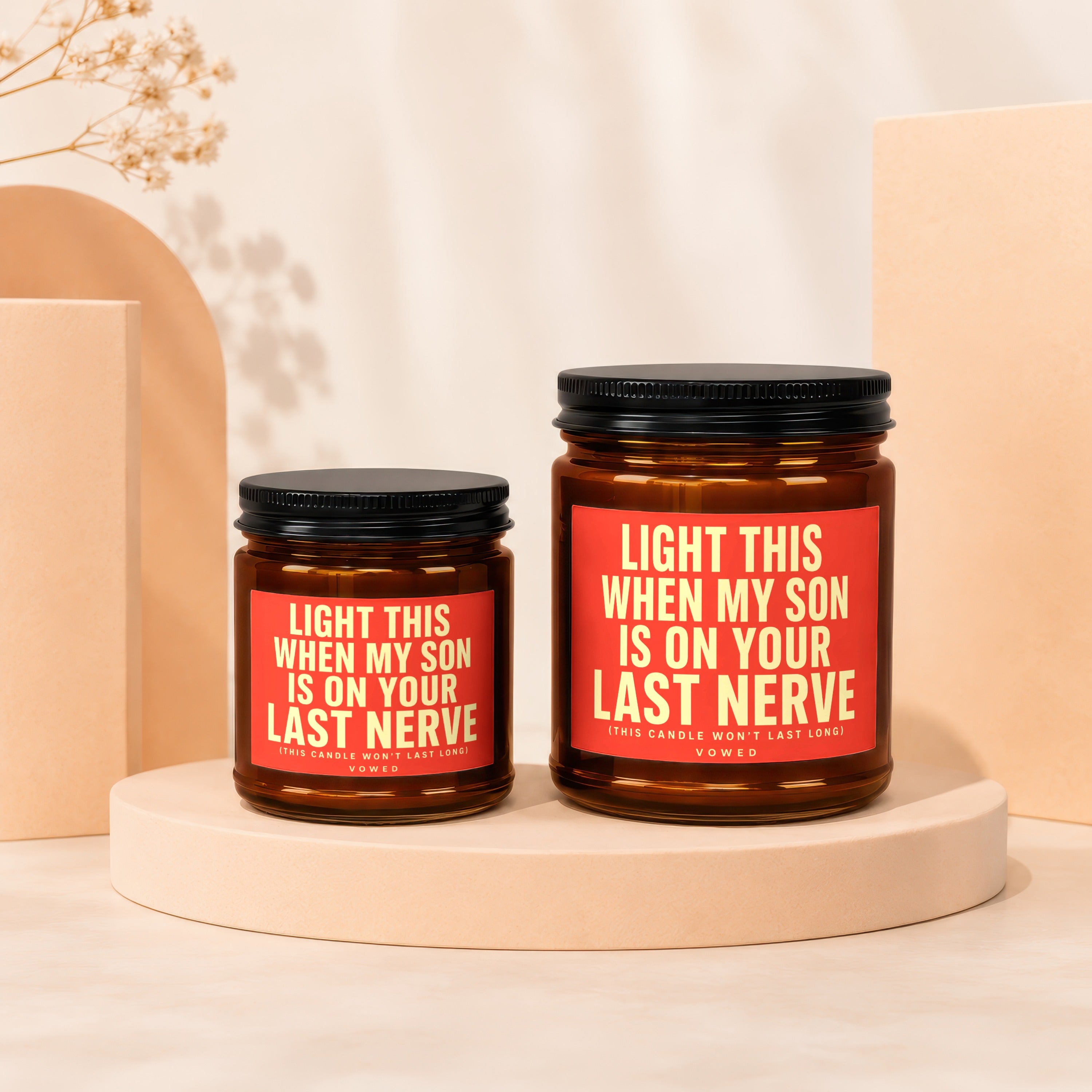 Two amber glass candles with black lids and red labels.