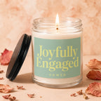 Glass jar candle with lit flame and "Joyfully Engaged vowed" text.
