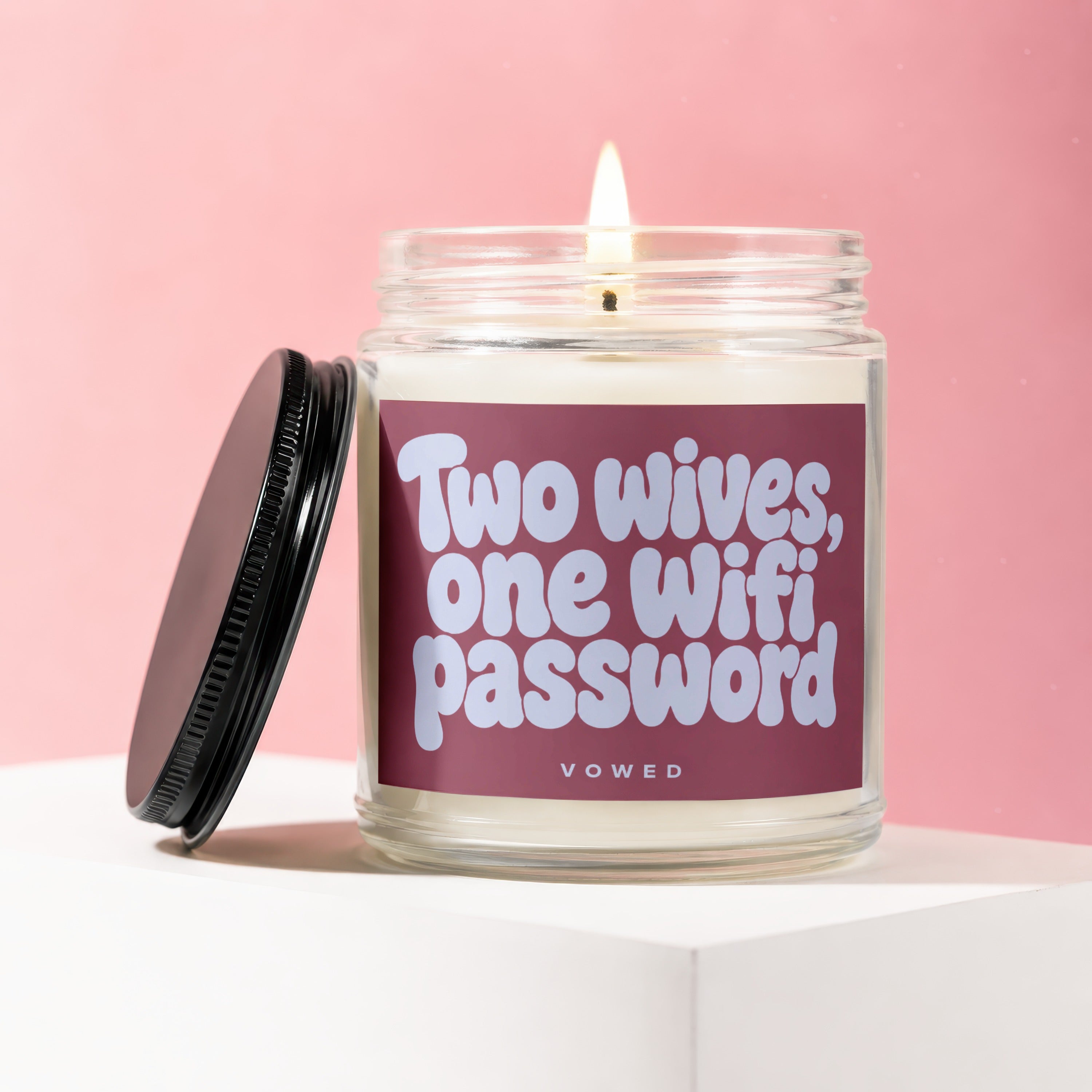Candle with text "Two wives, one wifi password" on a pink background.