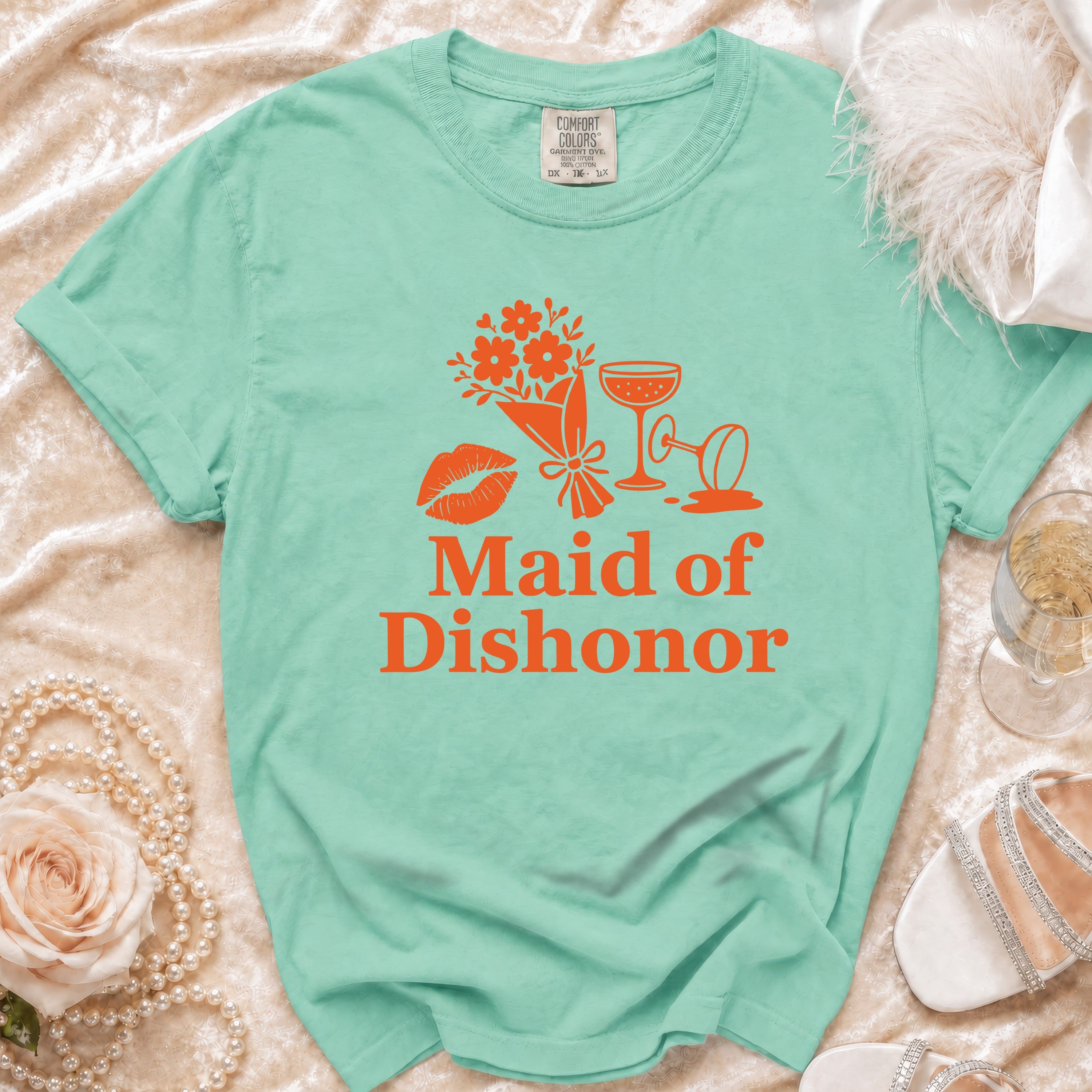 Teal t-shirt with graphic of flowers, lips, and champagne glasses, text "Maid of Dishonor."