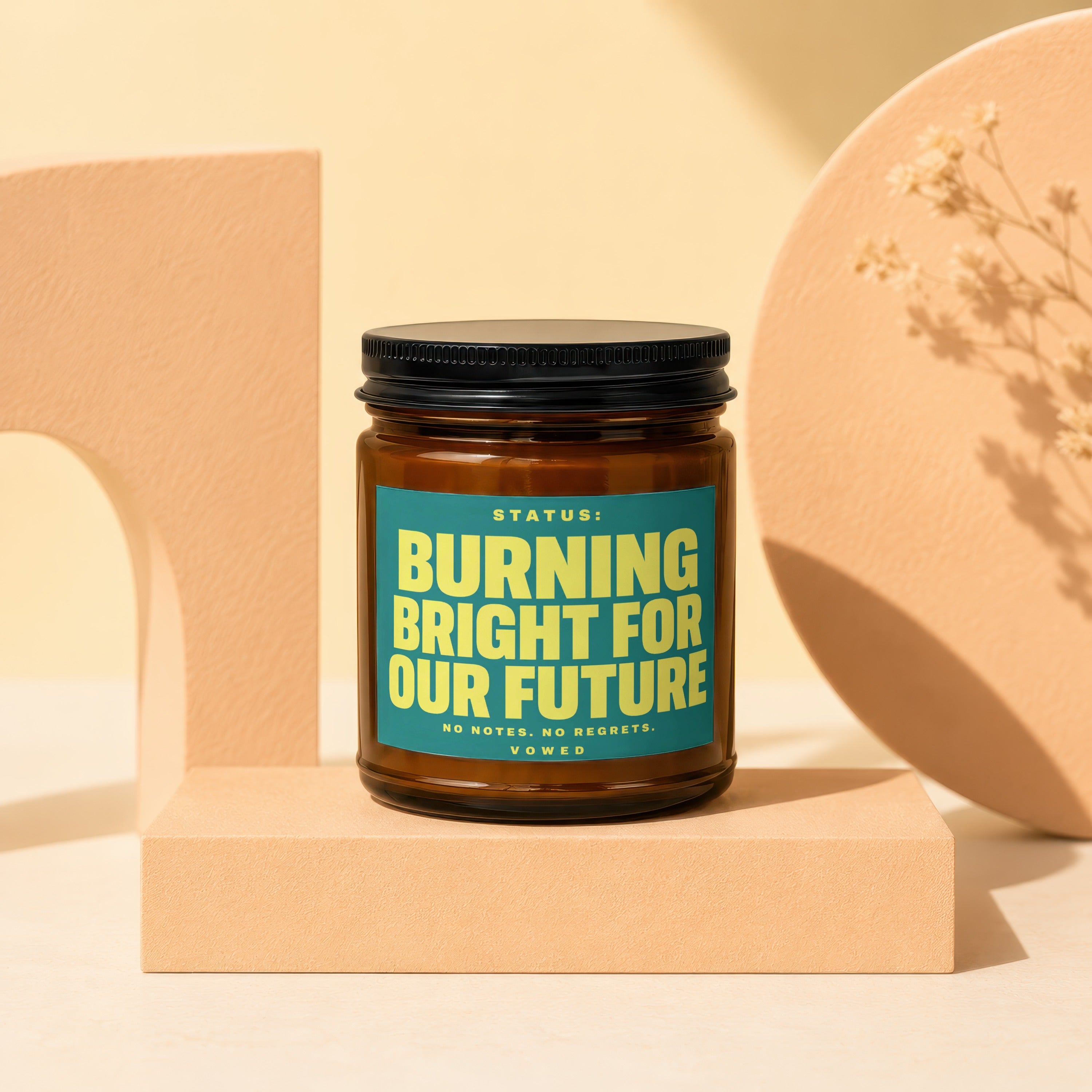 Amber jar candle with a teal label reading "Burning Bright For Our Future".