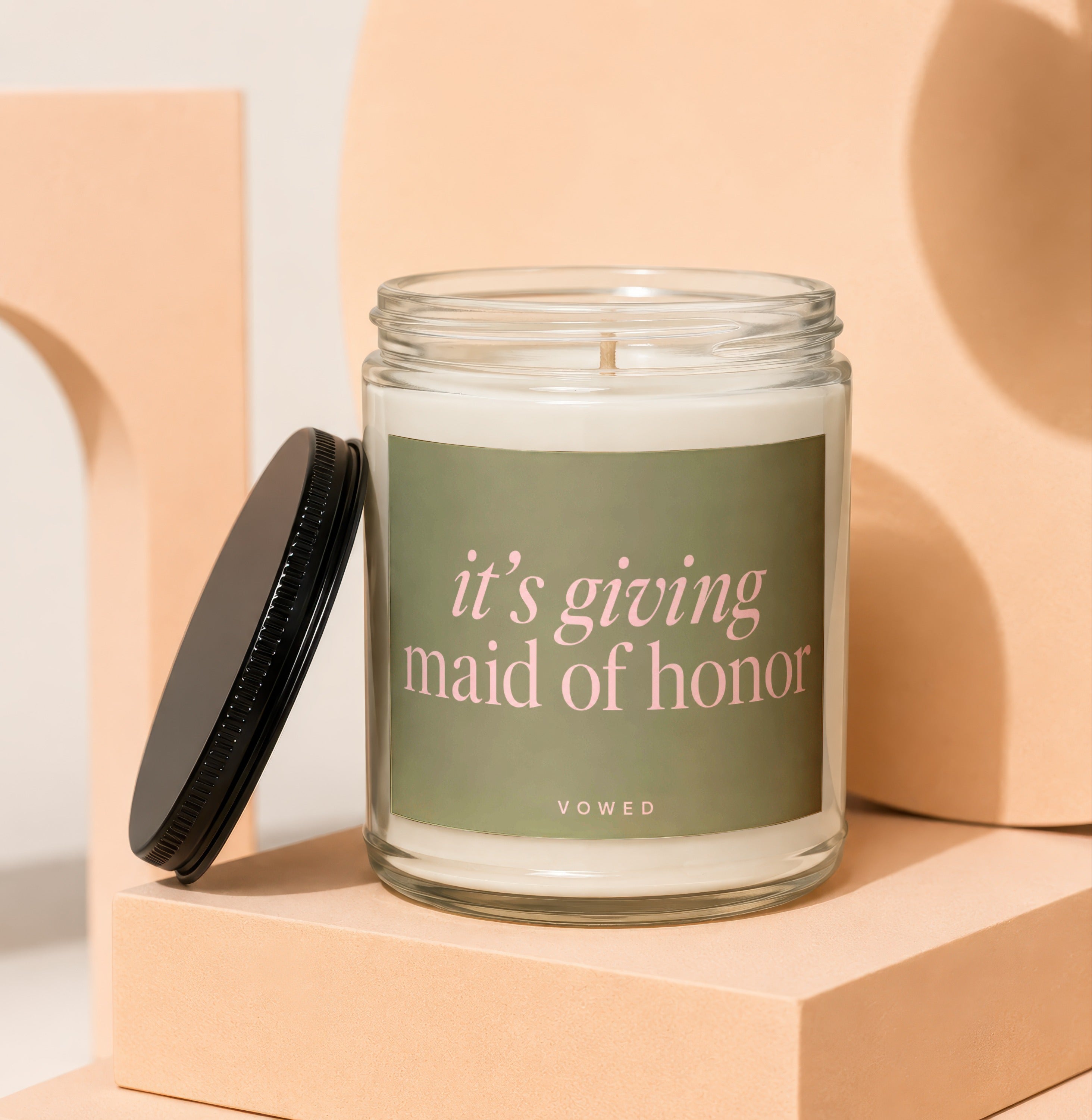 Glass candle with black lid, reads "it's giving maid of honor" and "VOWED".