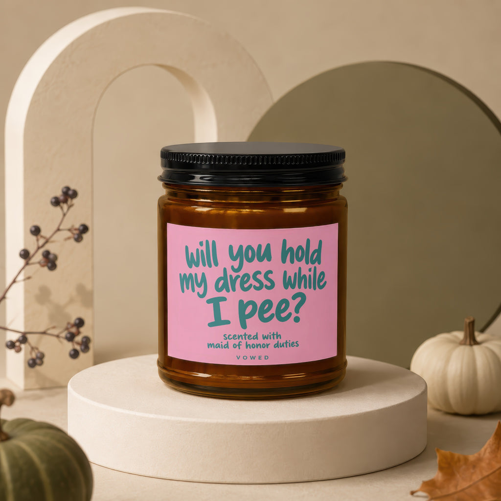 Scented candle with pink label asking, "will you hold my dress while I pee?"