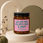 Scented candle with pink label asking, "will you hold my dress while I pee?"
