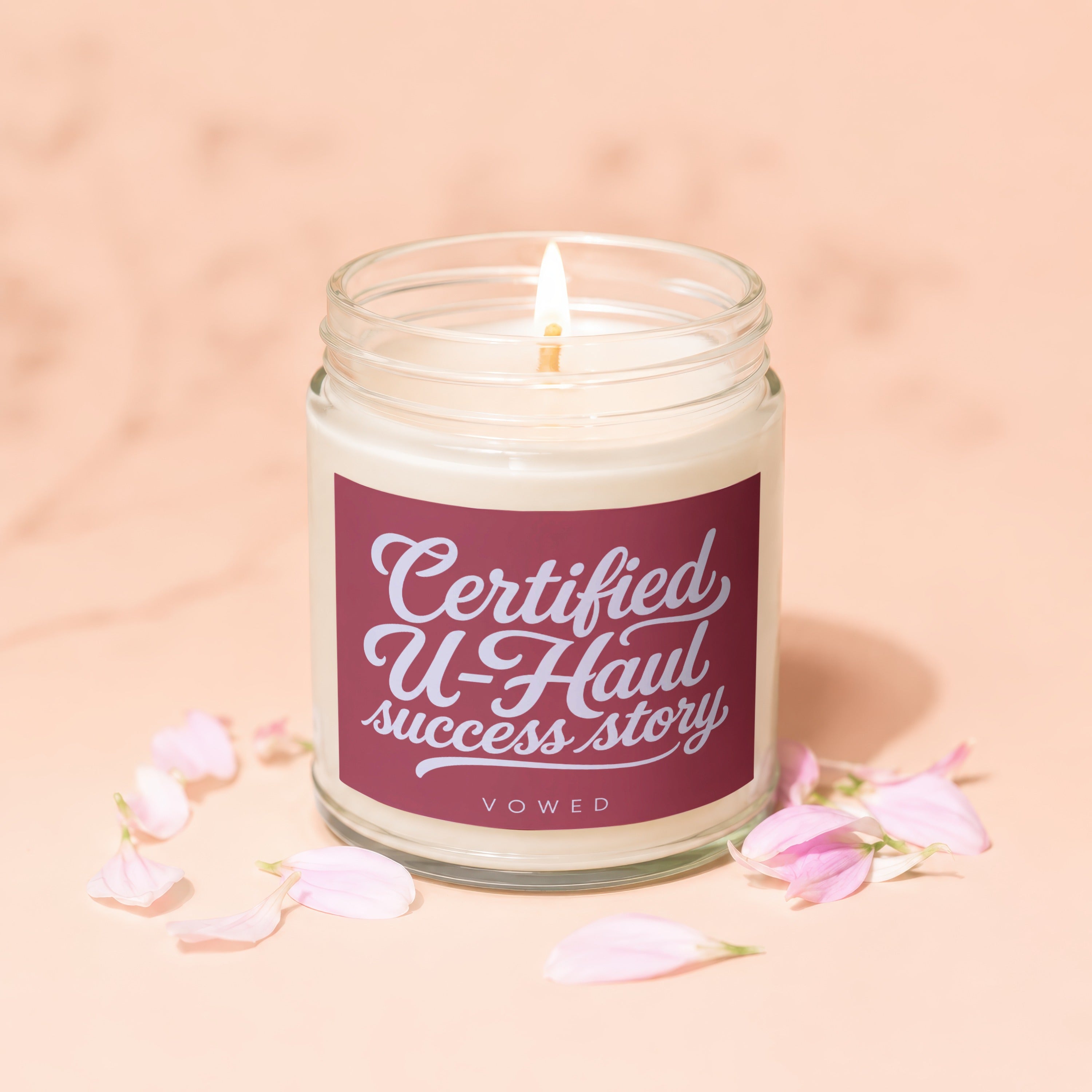 Glass jar candle with burgundy label reading "Certified U-Haul success story" and "VOWED".