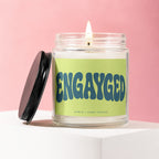 Candle with "ENGAYGED" text on a light green label, Vowed | Hand Poured.