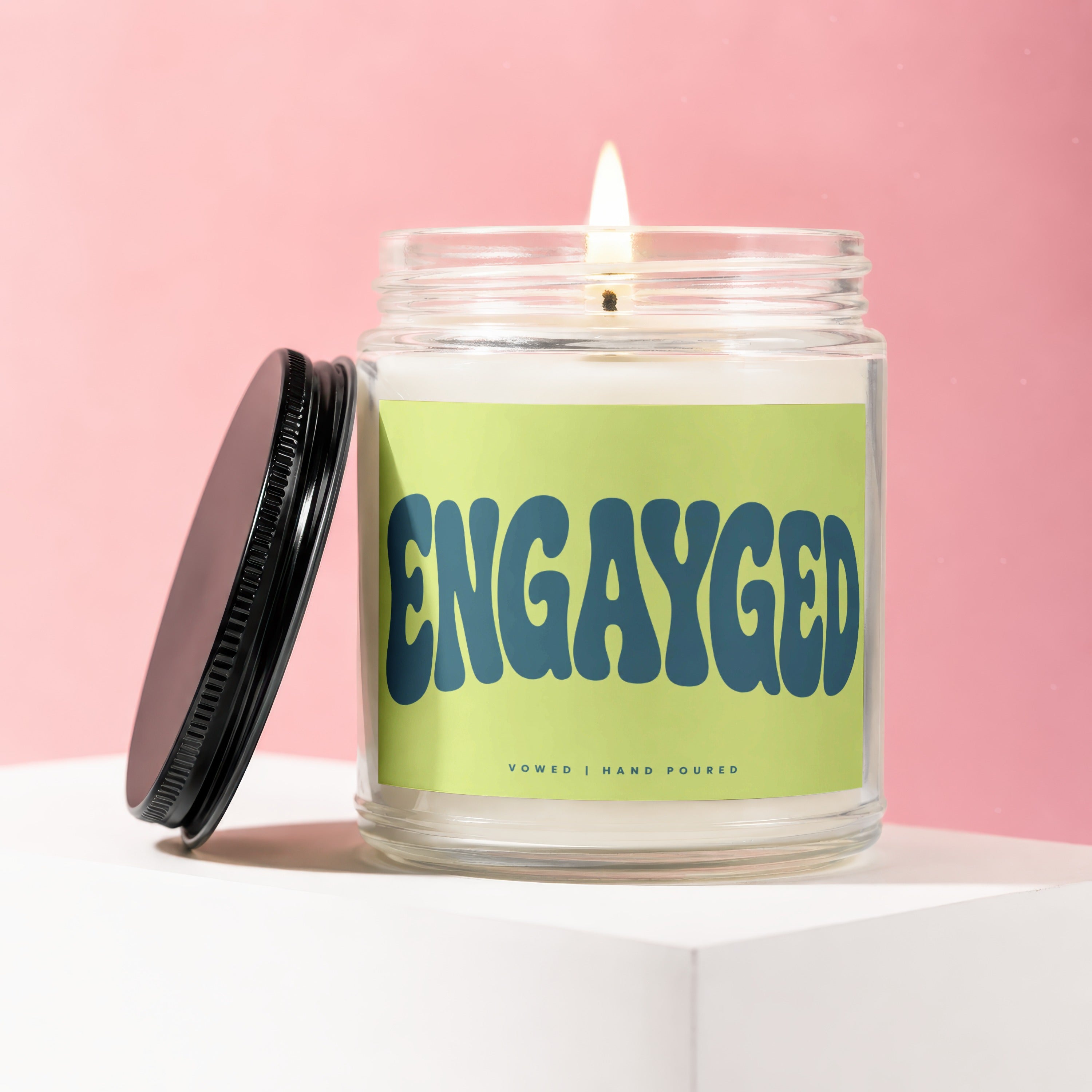 Candle with "ENGAYGED" text on a light green label, Vowed | Hand Poured.