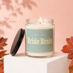 A lit candle labeled "Bride Brain" by Vowed, with its lid off.