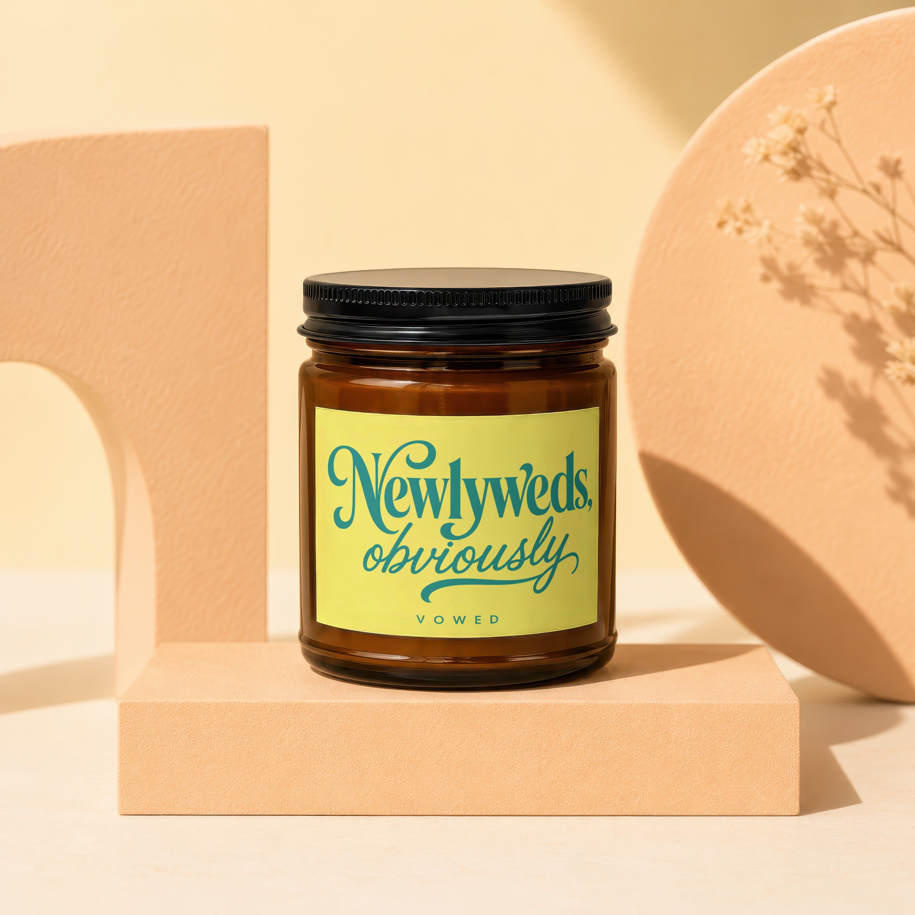 Amber glass candle with yellow label reading "Newlyaeds, obviously. VOWED".