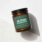 Amber glass candle with a dark green label that reads "Love, Officially."