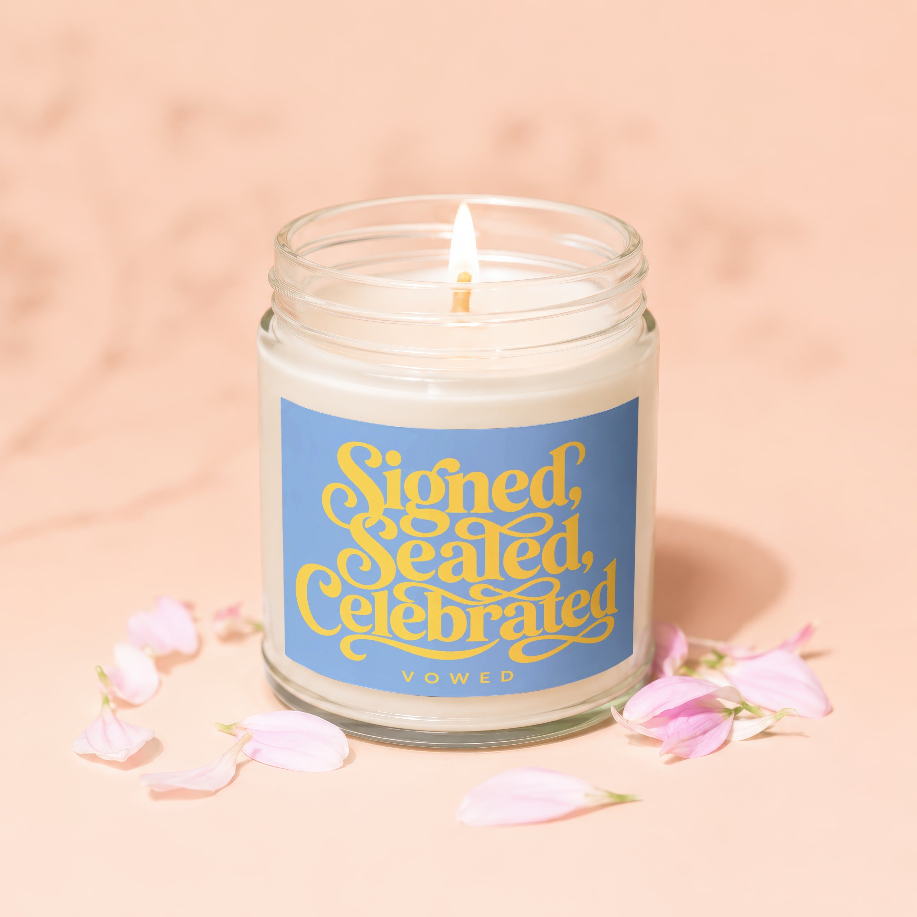 Lit candle with blue label saying "Signed, Sealed, Celebrated VOWED".