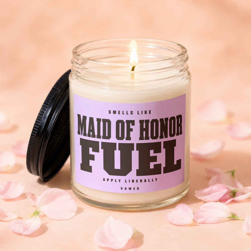Candle with "Maid of Honor Fuel" text on a pink label and a lit wick.