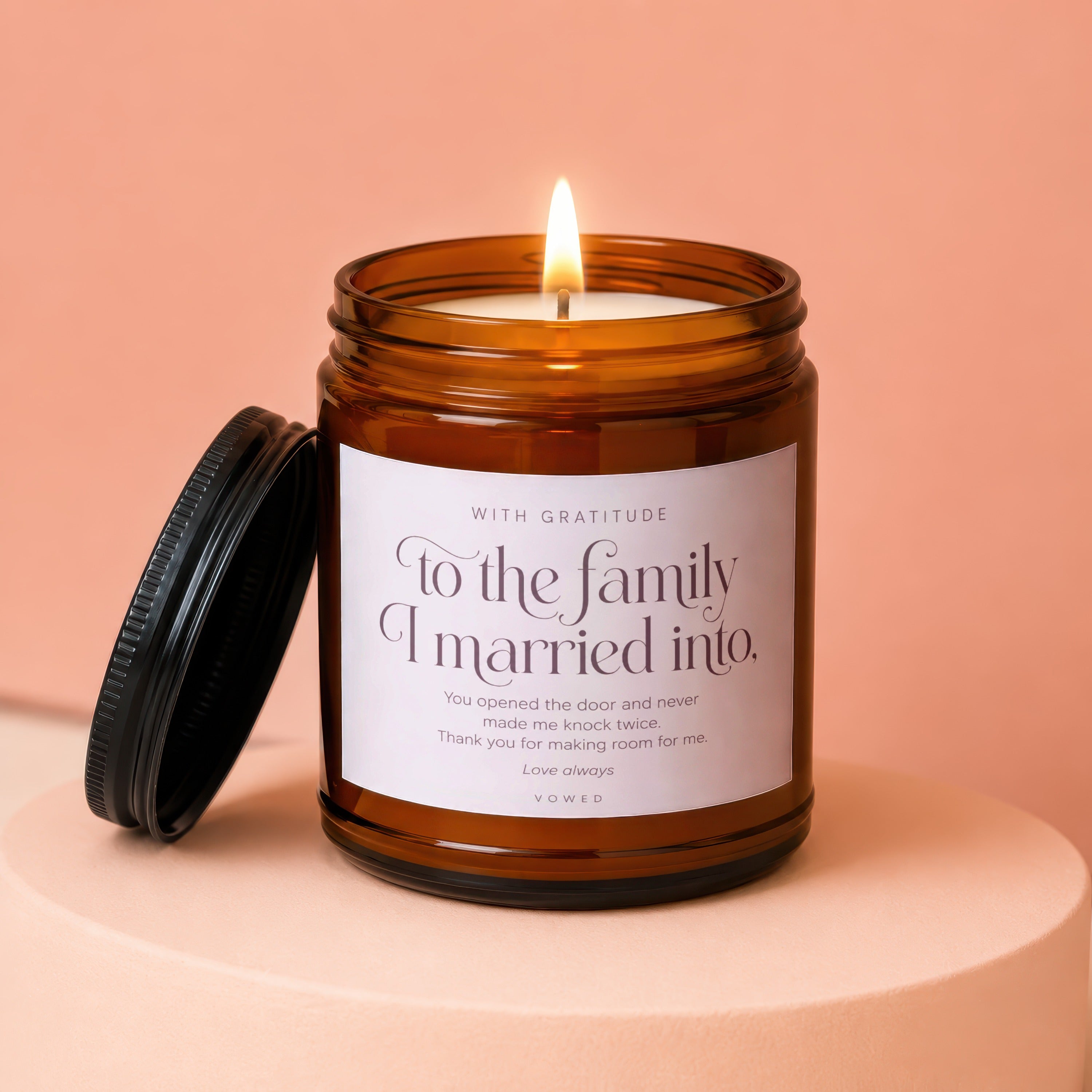 Amber jar candle with lit wick. Label reads "To the family I married into."
