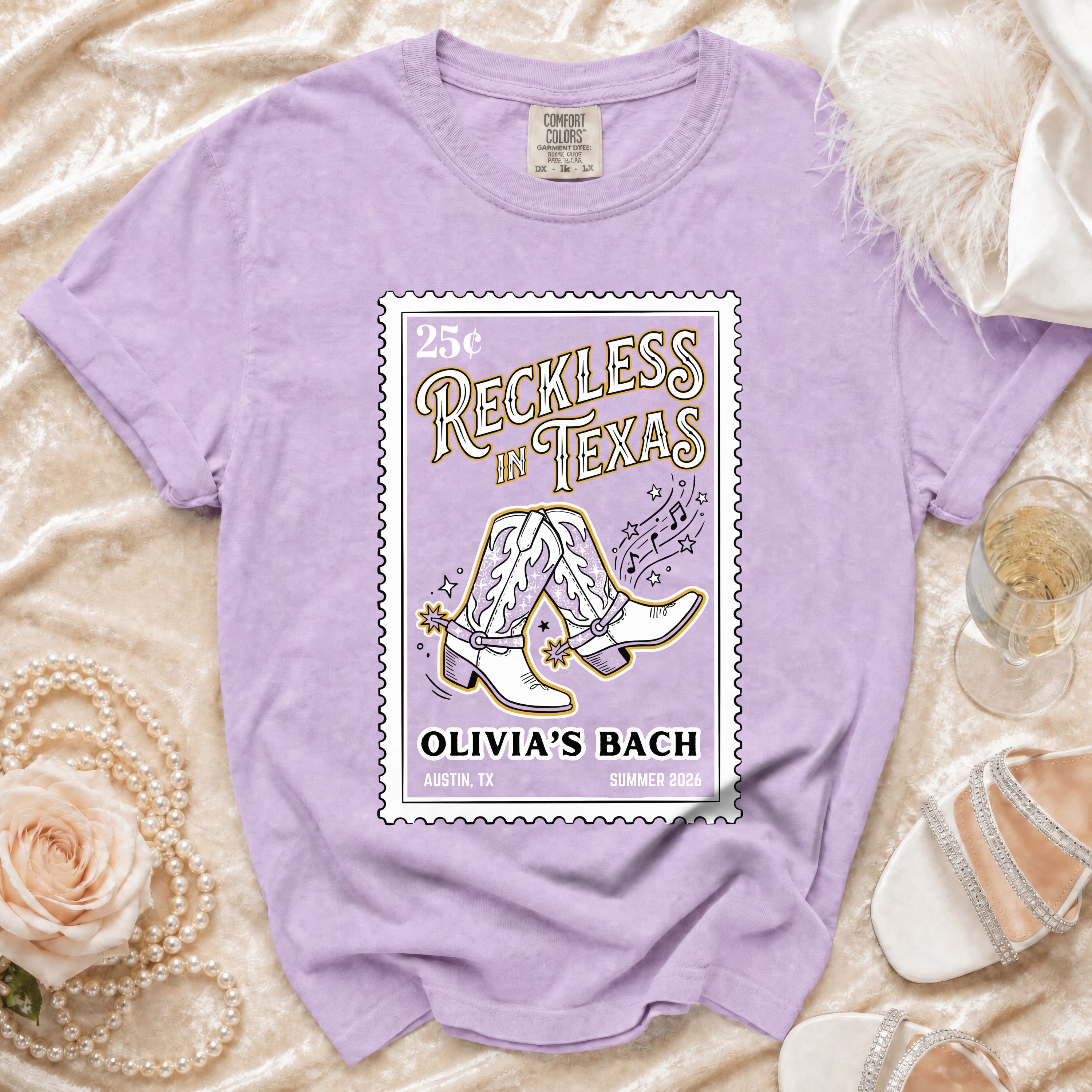 Purple t-shirt with "Reckless in Texas" graphic featuring cowboy boots.