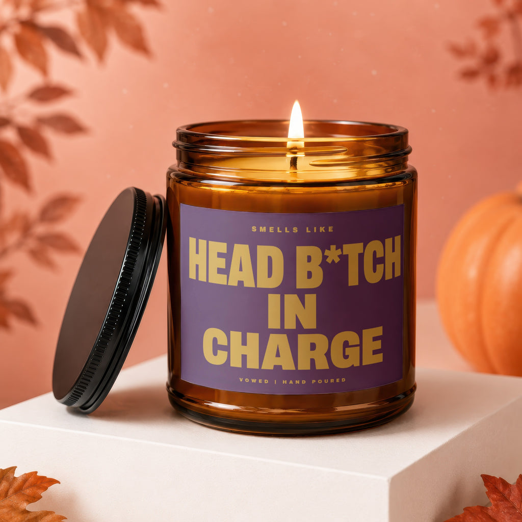 Amber glass candle with purple label reading "Smells Like Head B*tch In Charge."