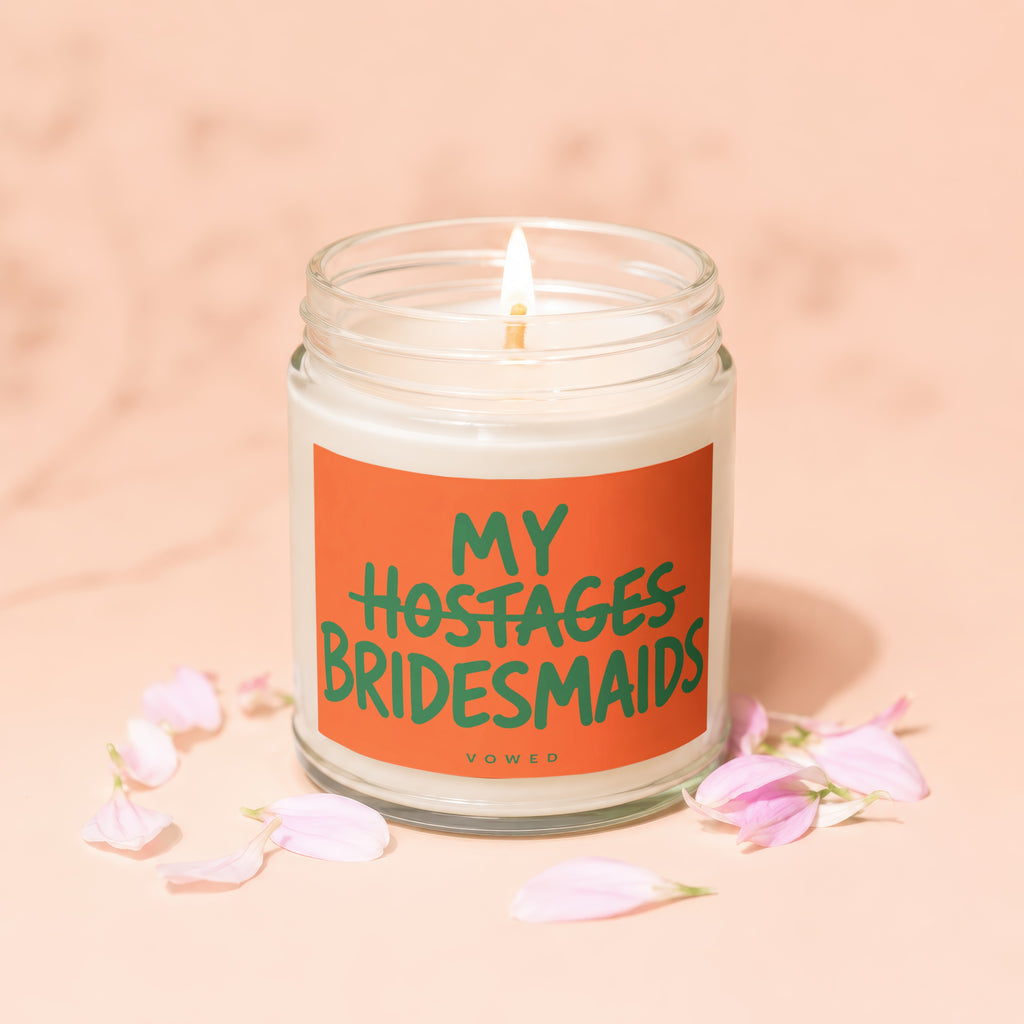 Candle with orange label reading "MY HOSTAGES BRIDESMAIDS VOWED".