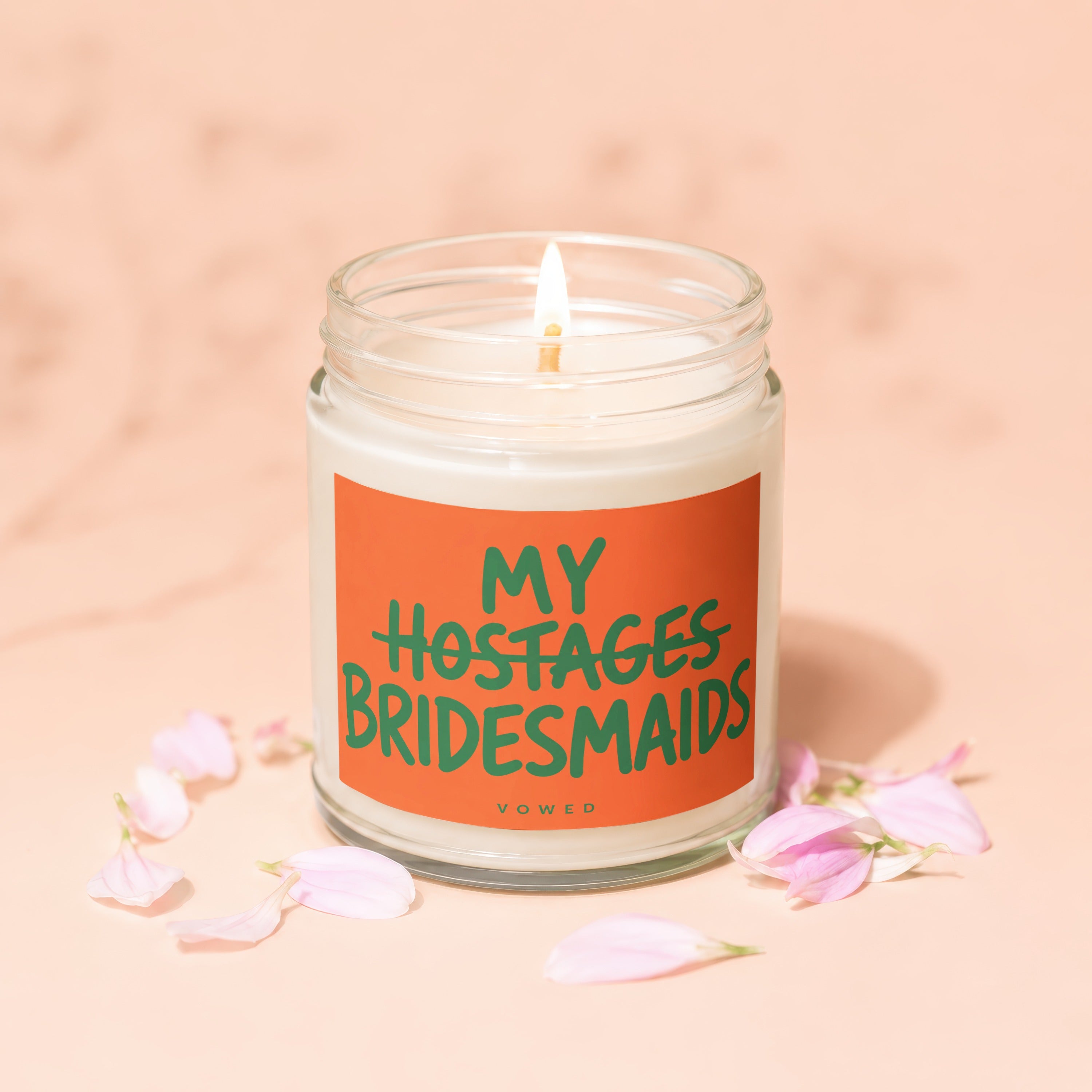 Candle with orange label reading "MY HOSTAGES BRIDESMAIDS VOWED".