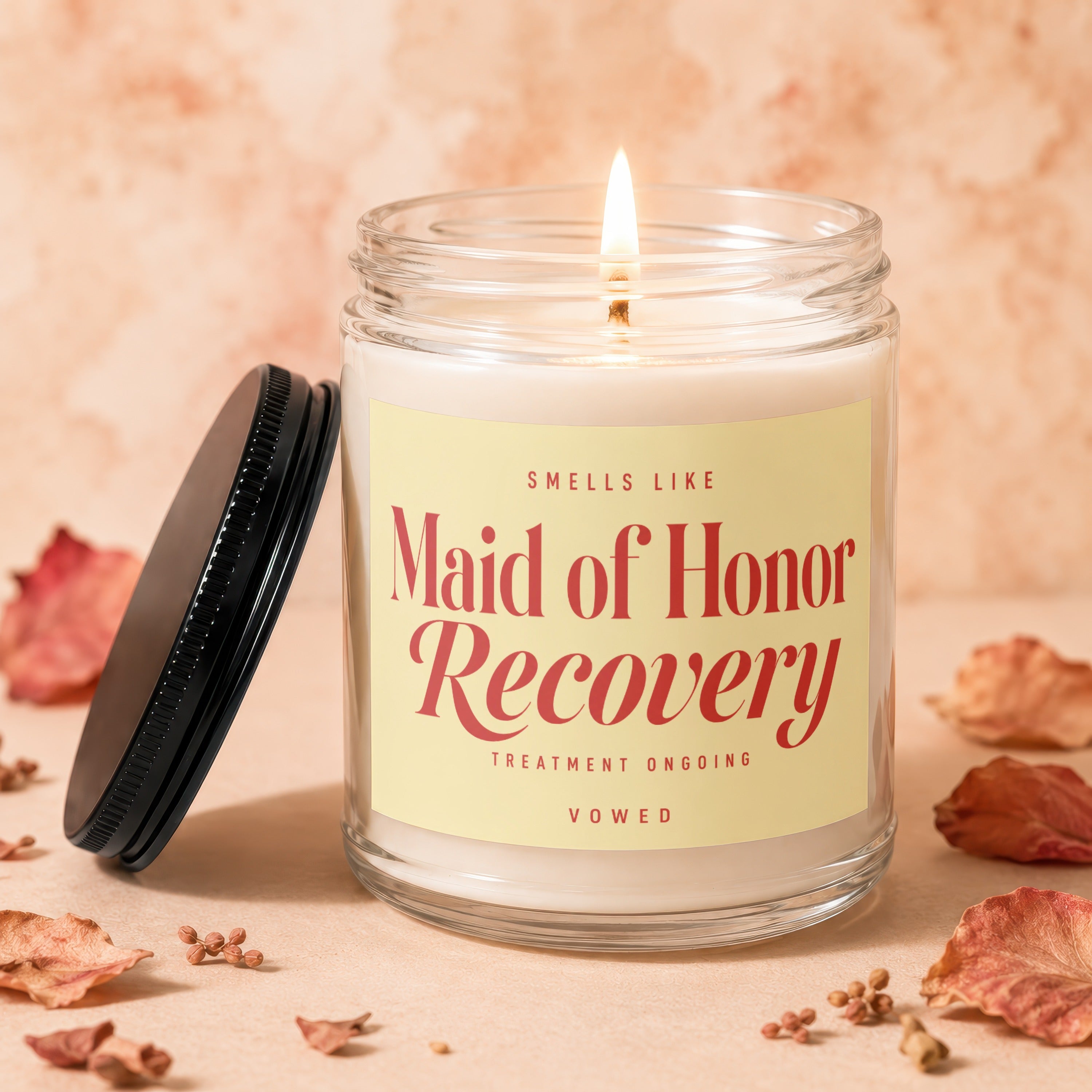 Jar candle with "Maid of Honor Recovery Treatment Ongoing" text, lid detached.